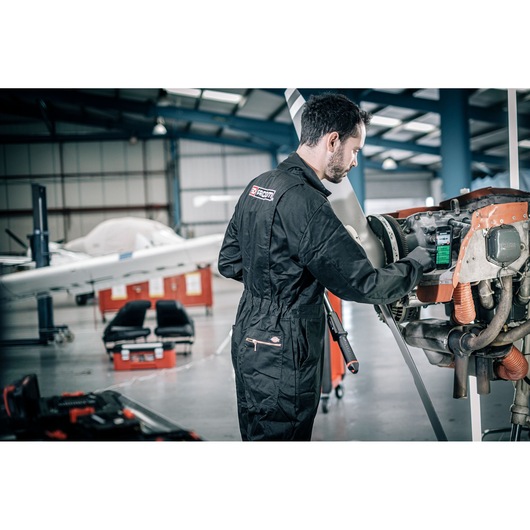 Facom E_516ST-340PB black coverall worn by mechanic working on aircraft engine in hangar.