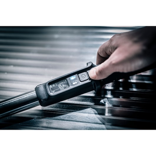 Facom digital torque wrench E_516ST-340PB close-up showing control screen and hand on metallic surface.