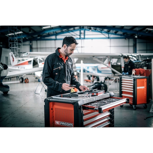 Facom E_516ST-340PB tool cabinet in workshop with open drawers and technician using tools.
