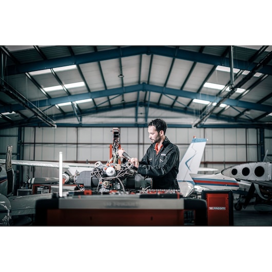Facom E_516ST-340PB photography of a mechanic working on an aircraft engine in a hangar.
