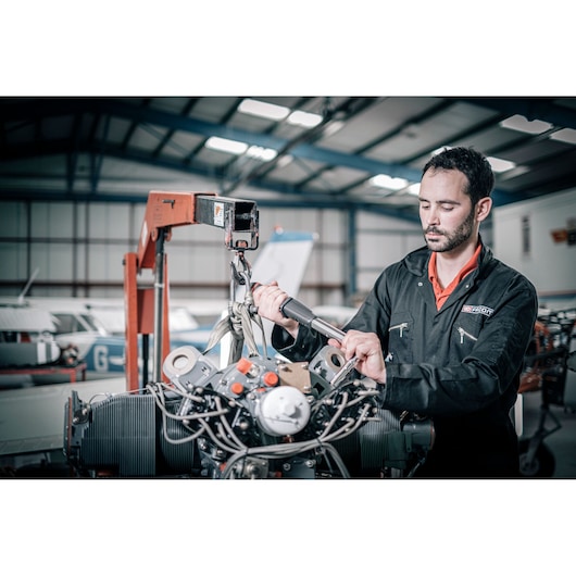 Facom E_516ST-340PB mechanic using torque wrench on aircraft engine in hangar.