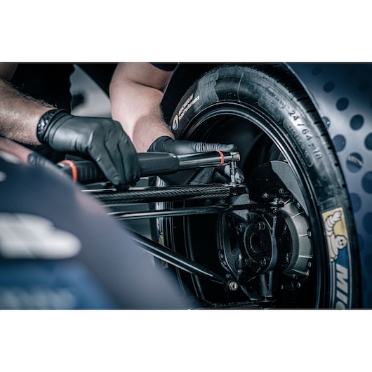 Facom E_516ST-340PB torque wrench in use on motorsport wheel, close-up photography with gloved hands.
