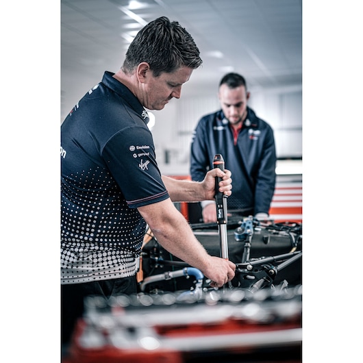 Facom E_516ST-340PB torque wrench in use by a mechanic in a workshop, visible branding on handle.