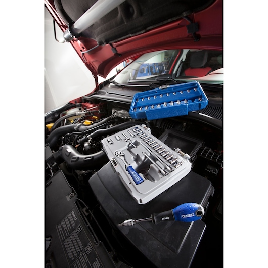 Facom E030702 socket and bit set with blue handles on car engine during maintenance, photography angle.