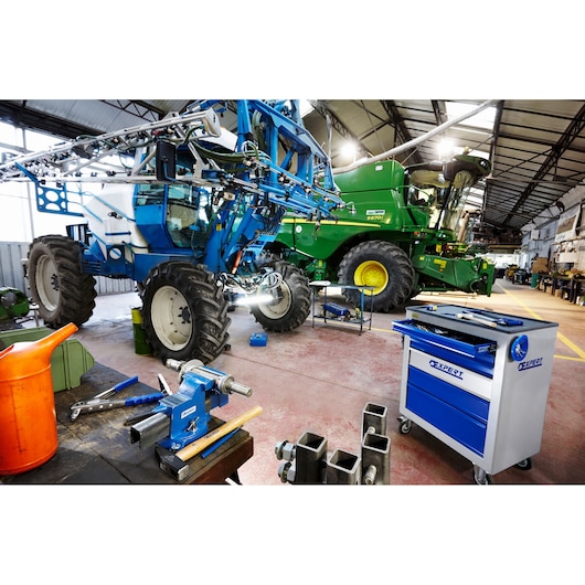 Facom E090404 blue and silver tool cabinet on wheels in a workshop with agricultural machinery and tools.