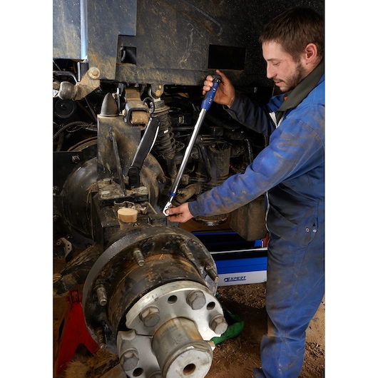 Facom torque wrench E100109 used by mechanic on heavy vehicle suspension part.