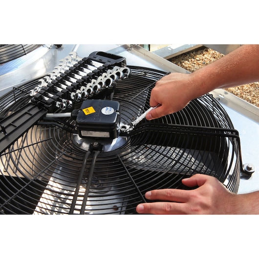 Facom E110908 ratcheting wrench set used on fan motor, close-up photo in maintenance setting.