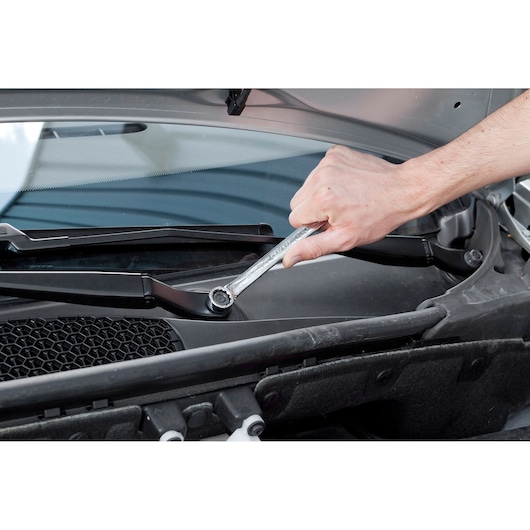 Facom E113200 ratcheting wrench in use tightening a nut on a car windshield wiper arm.