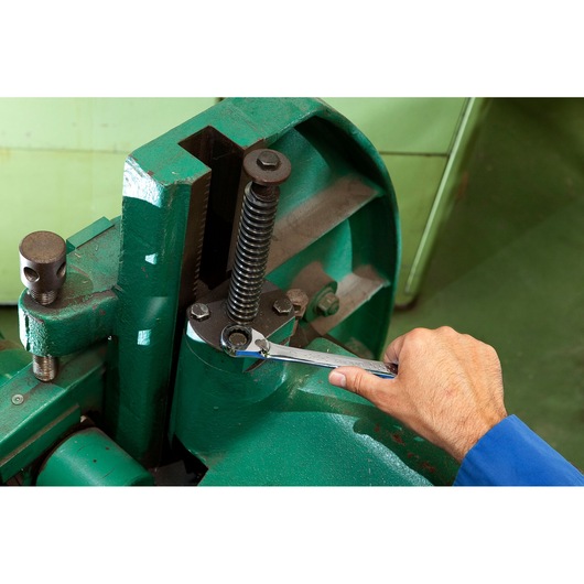 Facom E113305 wrench being used on a green industrial machine, close-up angle.