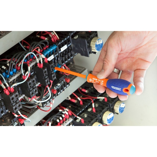 Facom E165422 insulated screwdriver with orange shaft and blue handle used for electrical panel maintenance.