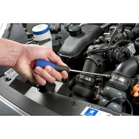 Facom E165479 screwdriver with blue and black handle in use tightening a clamp on a car engine.