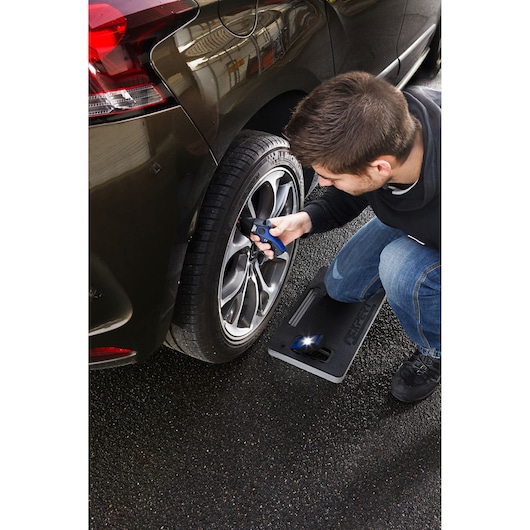 Facom E201120 kneeling mat in use beside a car wheel, with person checking tire pressure.