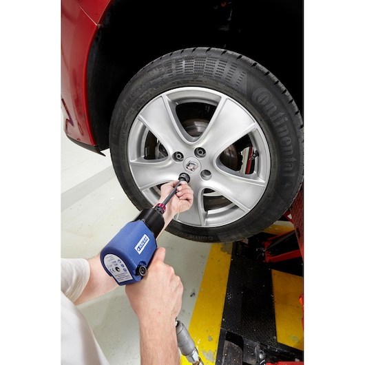 Facom E201129 impact wrench used on car wheel, hand visible, close-up photo.