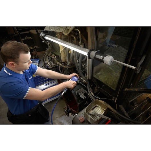 Facom E230104 photography of mechanic using blue pneumatic tool under bright LED work light in workshop.
