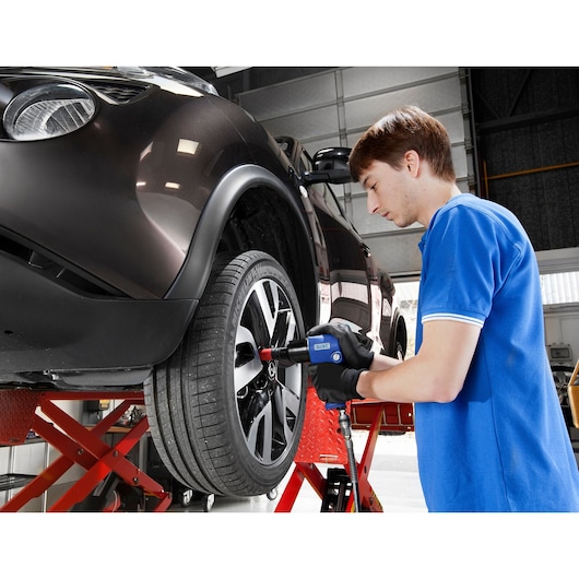 Facom E230110 impact wrench used by technician on car wheel in workshop.