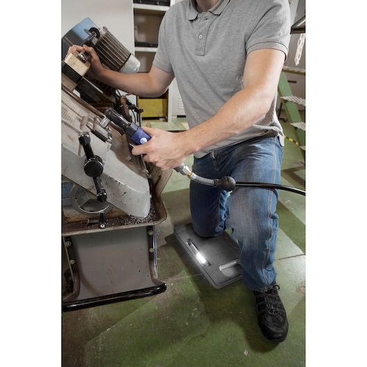 Facom E230204 kneeling pad used by worker in workshop, gray pad visible on green floor.