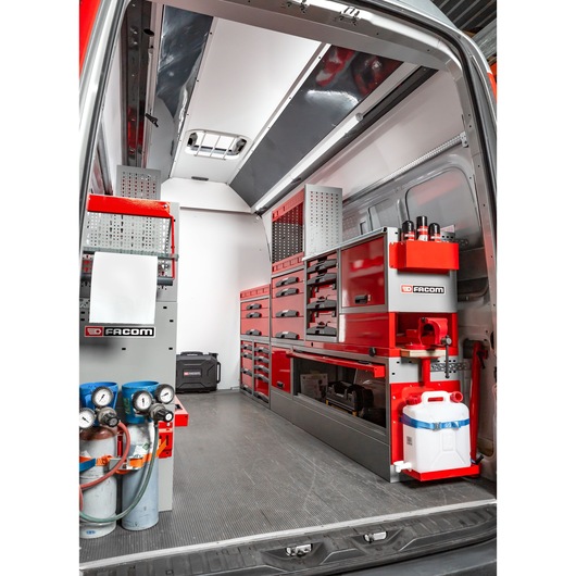 Interior view of a Facom-branded mobile workshop installed in a van, featuring organized red and grey storage cabinets, drawers, tool holders, gas cylinders, and a water container.