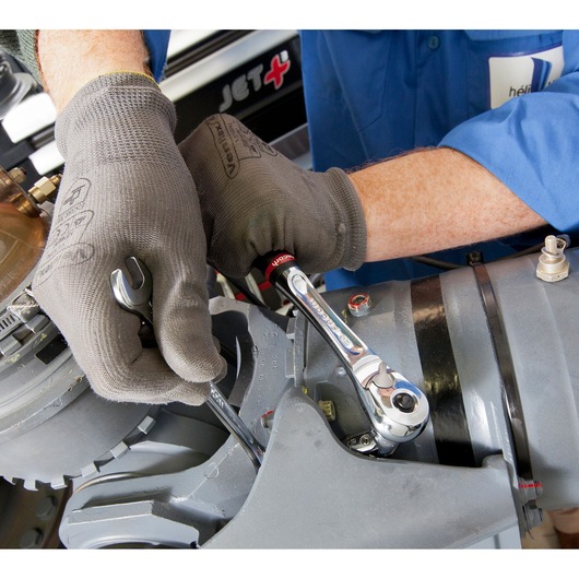 Facom J.1/2F ratchet wrench used by technician with gloves working on industrial machinery, side angle.