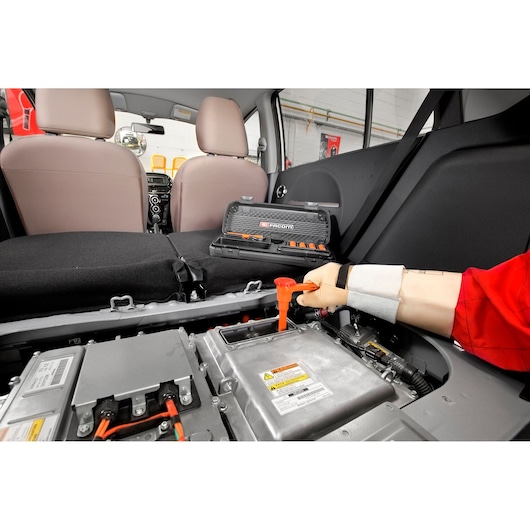 Facom J_151AVSE insulated tool set used on car battery, automotive interior visible.
