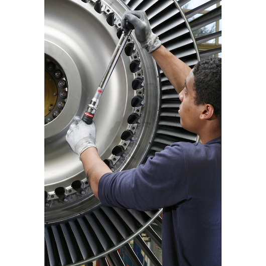 Photo of Facom J306A100 torque wrench used on a large industrial turbine by a gloved worker.