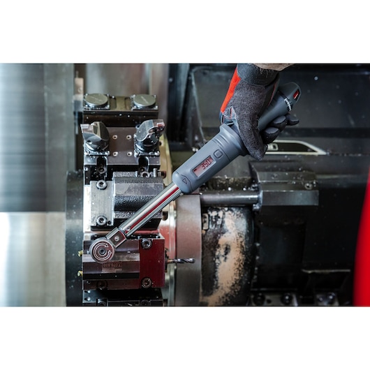 Facom J.307-50D digital torque wrench in use on industrial machinery, close-up of operator hand.