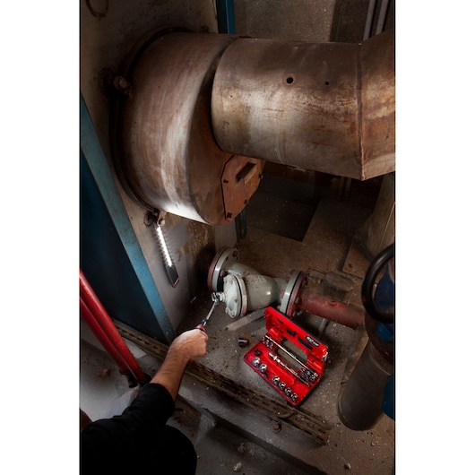 Facom red toolkit JXL_DBOX1 in use on industrial piping, visible sockets and ratchet in photography.