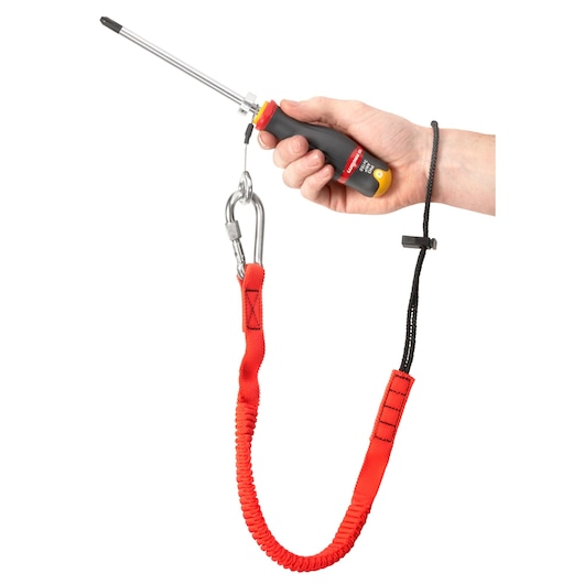 Photo of Facom LAN-WRT12 safety tether with red strap, carabiner, and hand loop, shown securing a screwdriver.