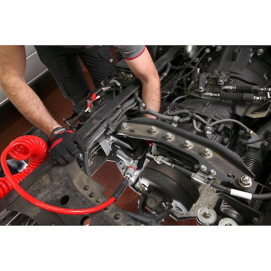 Facom NJ_1400F2 photography of gloved hands working with red coiled air hose on vehicle chassis.
