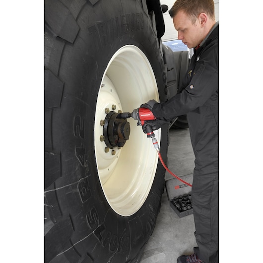 Facom NK.3000FPB pneumatic tool used on large tractor wheel, with socket set case on floor.