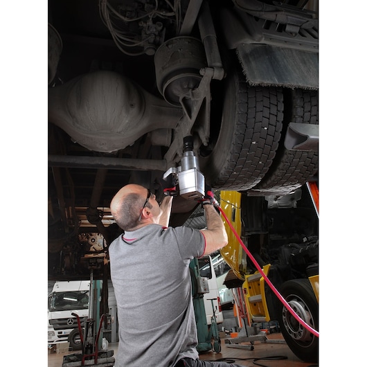Facom NM.1000F2PB pneumatic impact wrench in use on truck axle in workshop setting.