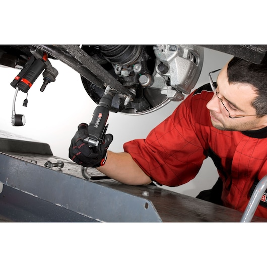 Facom NS_1400F mechanic tool used on car suspension by technician in red uniform.