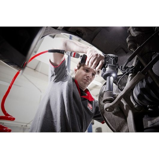 Photo of Facom NS.3500GPB mechanic using pneumatic tool on car suspension system in workshop.