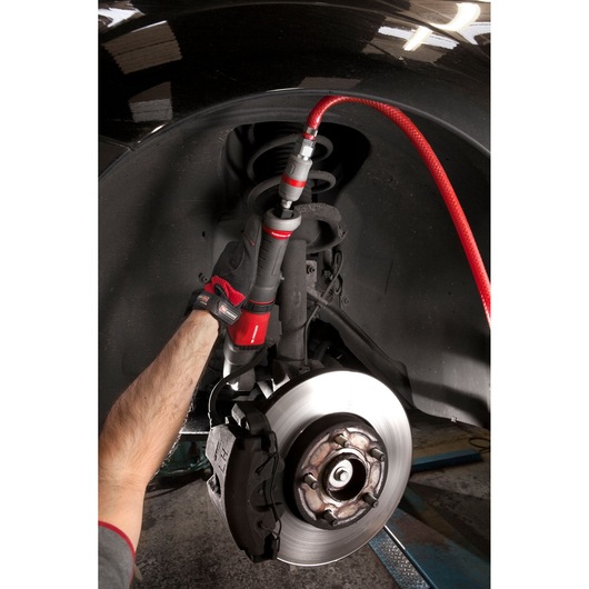 Facom NS.A1700F2PB air tool used on car suspension, close-up photography showing mechanic's gloved hand and brake disc.