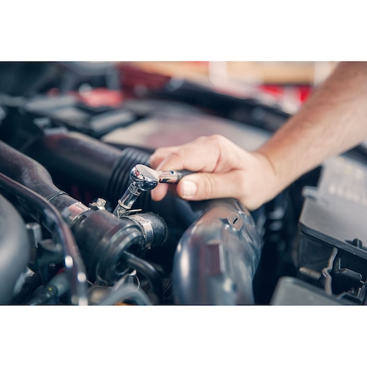 Photo of Facom R_181 ratchet wrench in use on car engine, close-up view