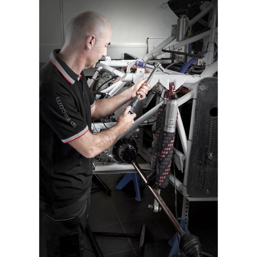 Photo of technician using Facom S.209-100D torque wrench on automotive frame, workshop setting.