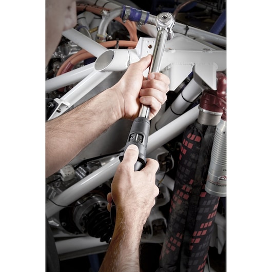 Facom S.209-100D torque wrench used on machinery, close-up view of hands adjusting tool.