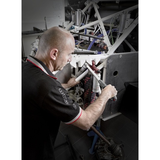 Facom S.209-340D torque wrench used by a mechanic on a white car frame in a workshop, side angle.