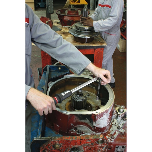 Facom S_215RC torque wrench used in industrial machinery assembly on workshop table.