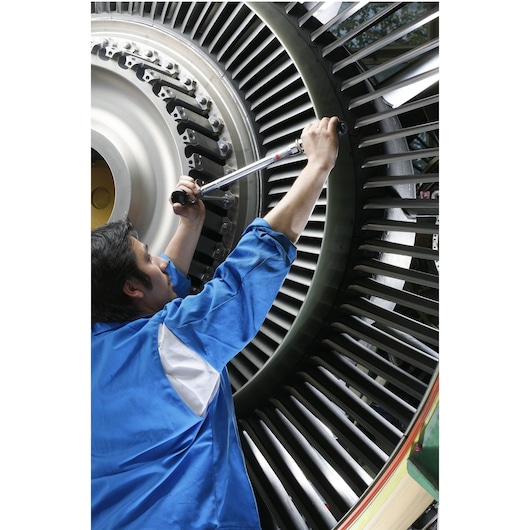 Facom S306A100 torque wrench used by technician on large industrial turbine, close-up angle.