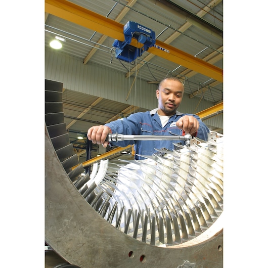 Facom S306A200 torque wrench used by worker in industrial setting, close-up view on turbine assembly.