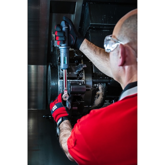 Facom S.307-100D torque wrench being used by a person in gloves and goggles to work on industrial machinery.