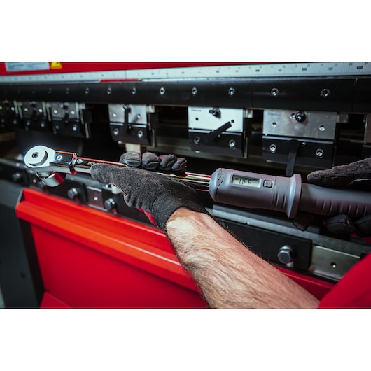 Facom S.307-200D digital torque wrench held by gloved hands in workshop setting.