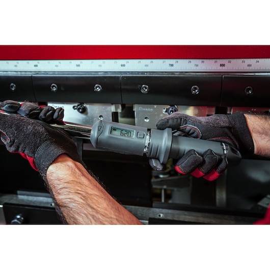 Facom S.307-340D electronic torque wrench with digital display held by gloved hands, close-up view.