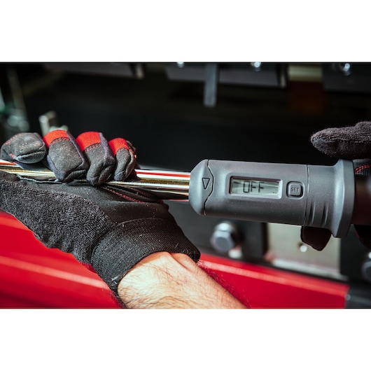Photo of Facom S.307A340 digital torque wrench, close-up of display and gloved hands holding tool.