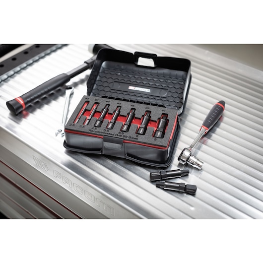Facom SXE_J7MGRPPB extraction socket set in open black case on metal workbench, with ratchet and loose sockets.