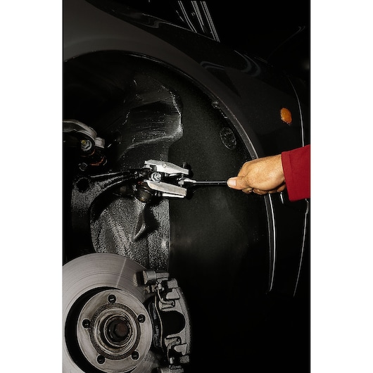 Facom U_16A18 automotive tool in use on vehicle wheel assembly, close-up, garage setting.