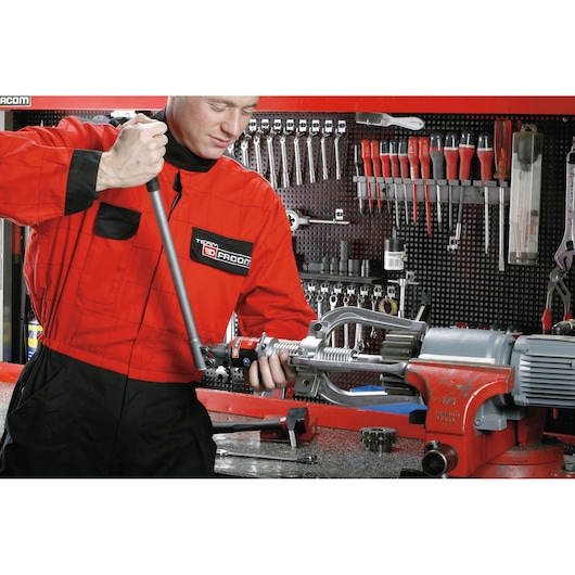 Facom U312H photography showing a technician in red coveralls using a tool in a workshop with organized hand tools.