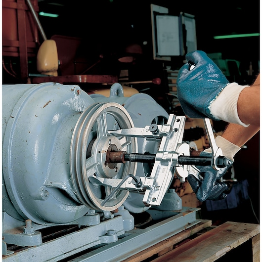 Facom U_32T15-25 gear puller tool in use on industrial machinery, worker wearing blue gloves.