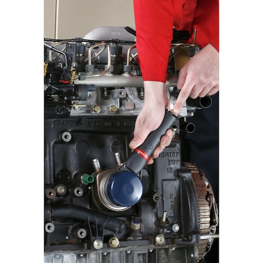 Facom U.48PB ratchet wrench used on a car engine, close-up photo of tool in operation.