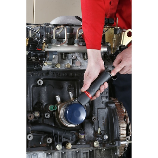 Facom U_48 oil filter wrench with black handle in use on engine, technician in red shirt demonstrating application.
